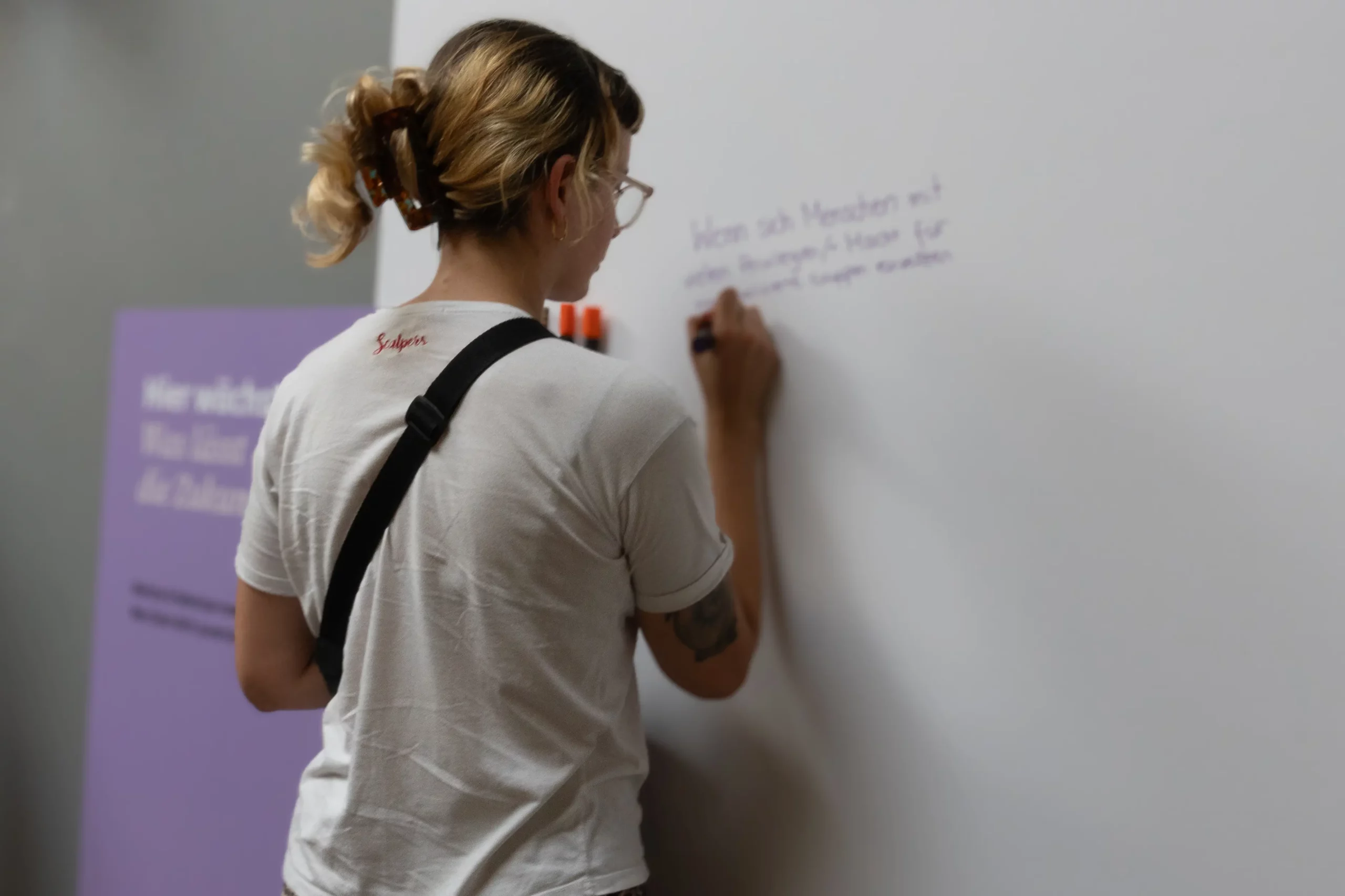 Frau schreibt etwas an eine weiße Wand