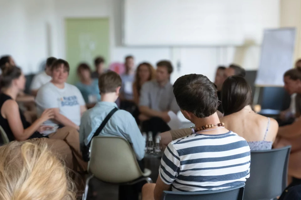 Blick in eine Konferenzsituation - Fish Tank. Menschen sitzen im Kreis und unterhalten sich