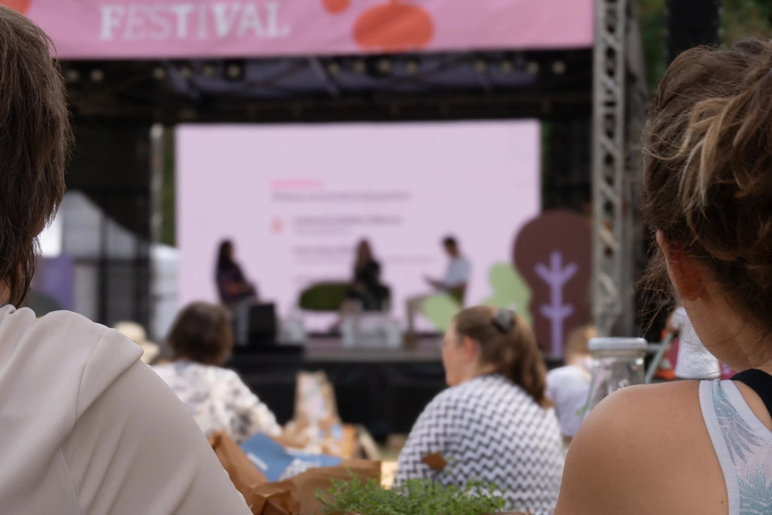 Menschen schauen auf Bühne mit Redner:innen, Bühne ist draußen