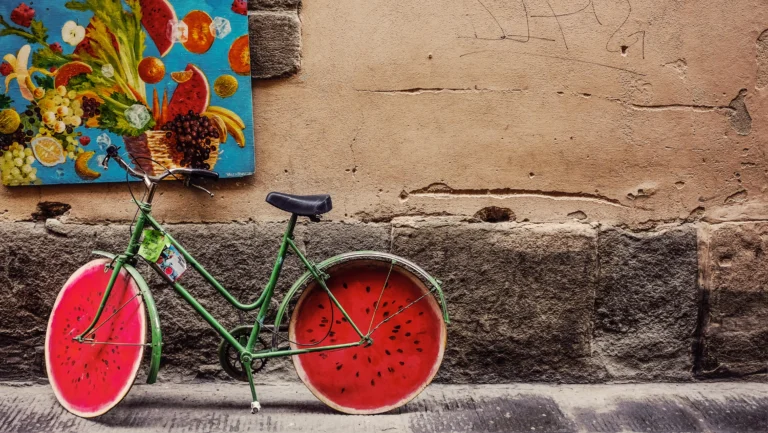 Fahrrad mit Wassermelonen Reifen und einem bunten Obst Bild im Hintergrund.